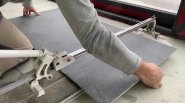 4k video footage of taking measurements for further cutting tiles using a diamond cutter. Laying tiles by a professional tiler in a modern interior.