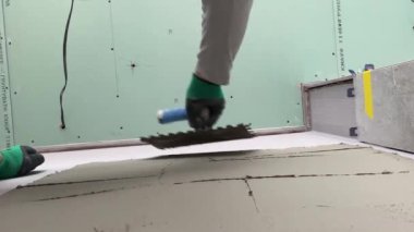 4k video footage of laying a large wide-format tile on a mounting mortar. Tiler laying tiles on cement mortar for gluing tiles on a surface