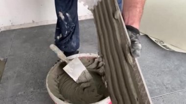 4k video footage of laying a large wide-format tile on a mounting mortar. Tiler laying tiles on cement mortar for gluing tiles on a surface