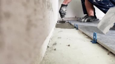 4k video footage of laying a large wide-format tile on a mounting mortar. Tiler laying tiles on cement mortar for gluing tiles on a surface