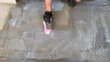 Construction works. 4k video footage with priming the floor surface before further finishing work. The builder is priming the floor with a brush