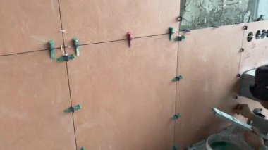 4k video footage of laying a large wide-format tile on a mounting mortar. Tiler laying tiles on cement mortar for gluing tiles on a surface