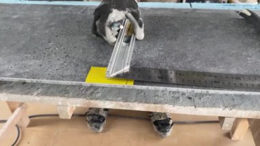 4k video footage of taking measurements for further cutting tiles using a diamond cutter. Laying tiles by a professional tiler in a modern interior.
