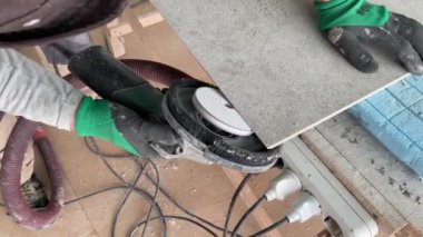 Tiling work. 4k video footage of grinding cuts at 45 degrees in tiles. Builder tiler cuts a large porcelain stoneware tile with a grinder