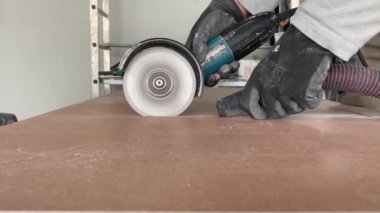 4k video footage of taking measurements for further cutting tiles using a diamond cutter. Laying tiles by a professional tiler in a modern interior.