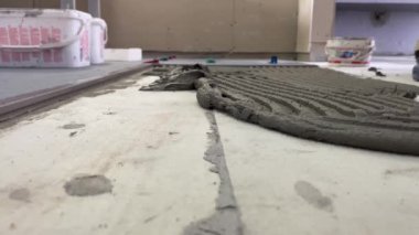 4k video footage of laying a large wide-format tile on a mounting mortar. Tiler laying tiles on cement mortar for gluing tiles on a surface