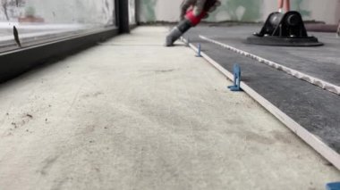 4k video footage of laying a large wide-format tile on a mounting mortar. Tiler laying tiles on cement mortar for gluing tiles on a surface