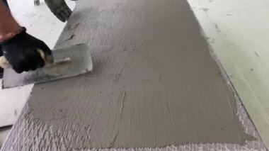 4k video footage of laying a large wide-format tile on a mounting mortar. Tiler laying tiles on cement mortar for gluing tiles on a surface