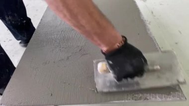 4k video footage of laying a large wide-format tile on a mounting mortar. Tiler laying tiles on cement mortar for gluing tiles on a surface