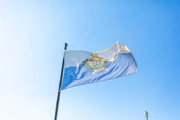 stock image Flag of San Marino in front of blue sky fluttering in the wind