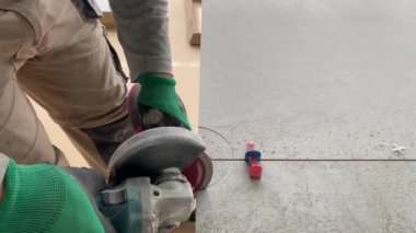 4k video footage of taking measurements for further cutting tiles using a diamond cutter. Laying tiles by a professional tiler in a modern interior.