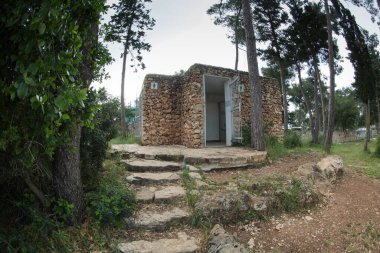 Ormanda, ağaçların arasında, tuğladan yapılmış umumi bir tuvalet var.