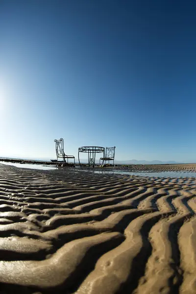 Stock image on the coast of the Red Sea, in Sinai, at low tide, on the beautiful relief sand there are a vintage table and chairs for photo shoots