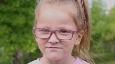 portrait of a cute little girl talking on the camera in a park 