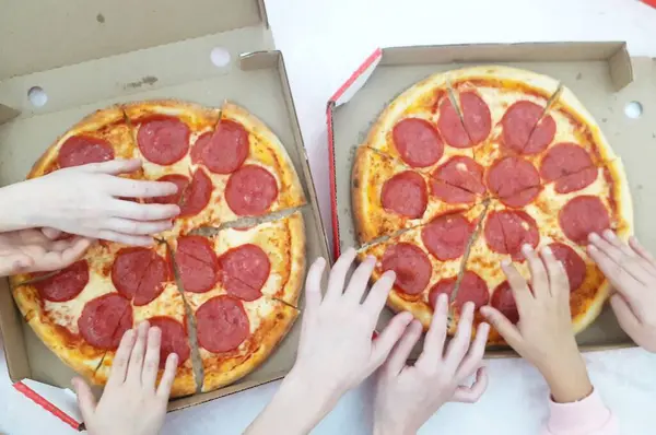 top view of kids hands on pizza, close up