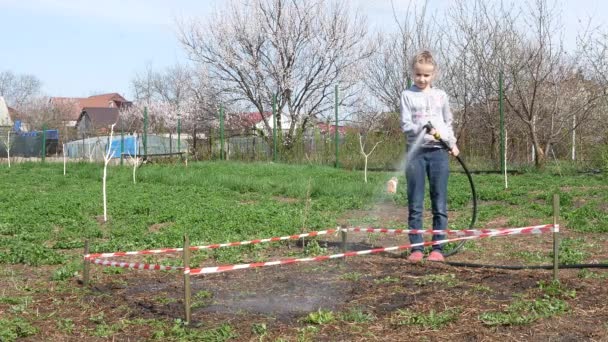 一个女孩正在用植物种子浇灌菜园 — 图库视频影像