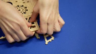 A child extracts elements from a child's wooden constructor blank.