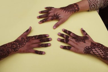 Henna mehendi dövmesinde elle boyanmış bir resim. Hint Mehendi kutlaması. Kına başvurusu ve ritüeller. Hintli gelin ve nedime kına sanatını gösteriyor
