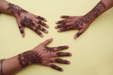 Henna mehendi dövmesinde elle boyanmış bir resim. Hint Mehendi kutlaması. Kına başvurusu ve ritüeller. Hintli gelin ve nedime kına sanatını gösteriyor