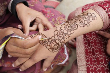 Henna mehendi dövmesinde elle boyanmış bir resim. Hint Mehendi kutlaması. Kına başvurusu ve ritüeller. Hintli gelin ve nedime kına sanatını gösteriyor