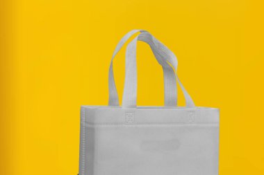 Assorted Color Non-Woven Fabric Shopping Bags isolated on yellow background. Tote Eco-Friendly Bags. Climate change disposable bags with yellow color background