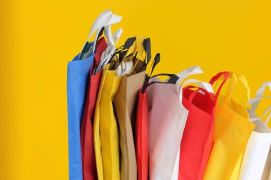 Assorted Color Non-Woven Fabric Shopping Bags isolated on yellow background. Tote Eco-Friendly Bags. Climate change disposable bags with yellow color background
