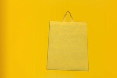 Assorted Color Non-Woven Fabric Shopping Bags isolated on yellow background. Tote Eco-Friendly Bags. Climate change disposable bags with yellow color background