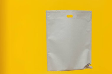 Assorted Color Non-Woven Fabric Shopping Bags isolated on yellow background. Tote Eco-Friendly Bags. Climate change disposable bags with yellow color background