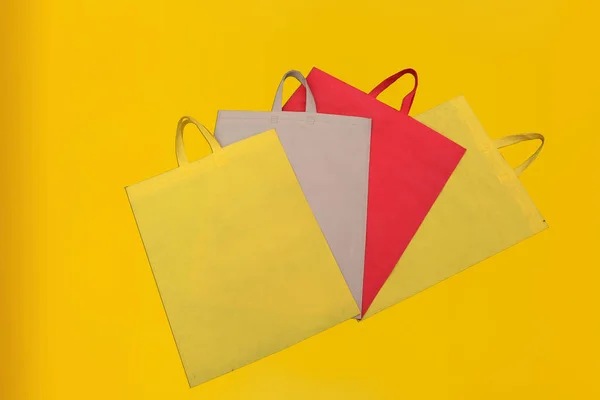 Assorted Color Non-Woven Fabric Shopping Bags isolated on yellow background. Tote Eco-Friendly Bags. Climate change disposable bags with yellow color background