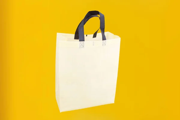 Assorted Color Non-Woven Fabric Shopping Bags isolated on yellow background. Tote Eco-Friendly Bags. Climate change disposable bags with yellow color background