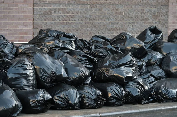 Black plastic trash bags full of garbage at the street