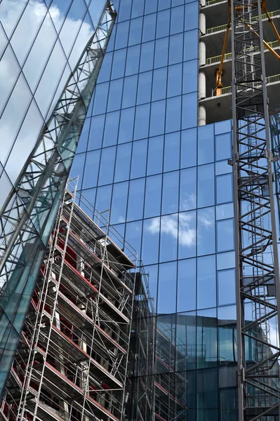 高層ビルの建設クレーンや建設 建設現場でガラスのファサードとクレーンと現代コンクリートの建物の都市景観モンタージュ — ストック写真