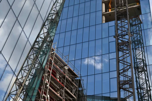 高層ビルの建設クレーンや建設 建設現場でガラスのファサードとクレーンと現代コンクリートの建物の都市景観モンタージュ — ストック写真