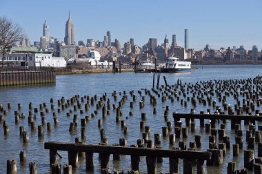 Hoboken, ABD - 15 Şubat 2023: Sudaki ahşap kutuplar ve Hoboken, New Jersey, ABD 'den Manhattan rıhtımına manzara