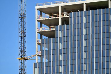 İnşaat vinci ve yüksek binaların inşaatı. İnşaat alanında cam cepheli ve vinçli modern beton bina manzarası.