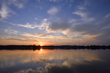 Gölün üzerinde yaz günbatımı. Batan güneşin son ışınları