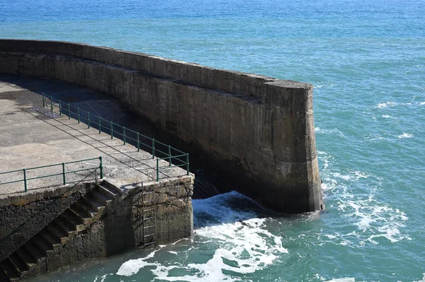 Protective concrete coastal pier breakwater, blue water in warm sunny weather, Madeira island