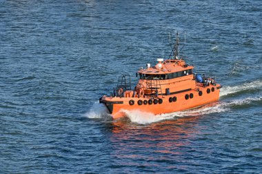 Orange rescue or coast guard patrol boat industrial vessel in blue sea ocean water clipart