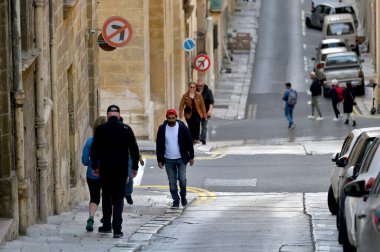 Valletta, Malta - 22 Aralık 2023: Malta adasının başkenti Valletta 'nın merkezinde dar bir sokakta kimliği belirsiz insanlar.