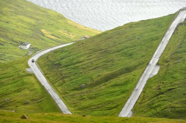 Tepelerin arasındaki yol. Eysturoy Adası, Faroe Adaları. Faroe Adaları, Atlantik Okyanusu 'nda bir volkanik takımada.. 