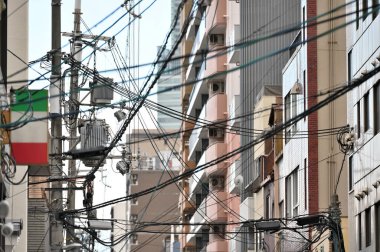 Sokakta kablolu ve lambalı elektrik direği, organize elektrik tesisatı Japonya 'nın parlak gökyüzü arka planında temizdir.