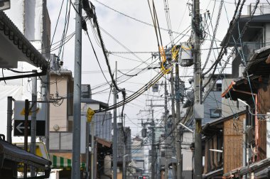 Sokakta kablo ve lambalar olan elektrik direkleri, Japonya 'nın parlak gökyüzü arka planında organize elektrik tesisatı temizdir.