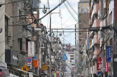 Osaka, Japonya - 18 Şubat 2025: Sokak ortasında elektrik direkleri ve lambalar, organize kablolar Japonya 'nın parlak gökyüzü arka planında düzgündür.