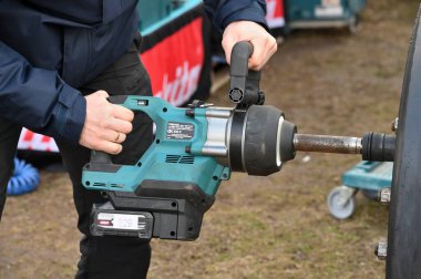 Kaunas, Litvanya - 27 Mart 2025: Litvanya 'nın Kaunas kentinde bir Makita profesyonel Etki Anahtarı kullanarak bir tekerlek somunu söken bir işçi