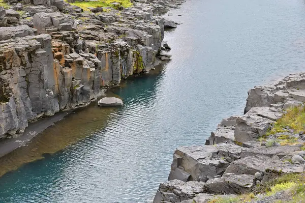 İzlanda 'daki vahşi nehir. İzlanda 'daki yeşil yosunlu tepenin aşağısından akan nehir.