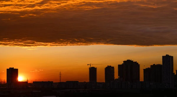City sunset silhouette under dramatic cloud mass