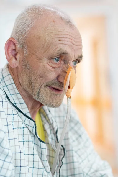 在医院病床上有鼻腹管的病人正在等待治疗 一个在等待手术的老年人的积极的特写 医院治疗的积极态度 免版税图库图片