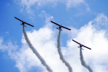 Liepaja, Letonya - 7 Ağustos 2022: Duman çizgili üç kırmızı spor uçağı Baltık Uluslararası Hava Gösterisi sırasında grup uçuşu yaptı