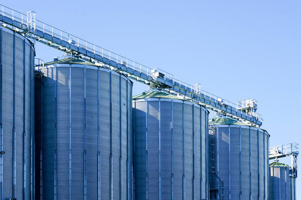 Agricultural silos, storage and drying of grains, wheat, corn, soy, sunflower against the blue sky background, grain dryer