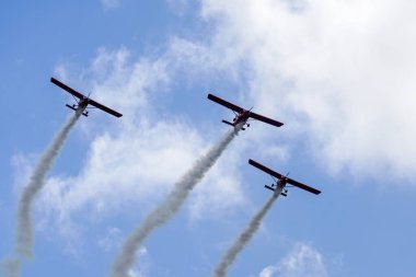 Liepaja, Letonya - 7 Ağustos 2022: Duman çizgili üç kırmızı spor uçağı Baltık Uluslararası Hava Gösterisi sırasında akrobatik grup uçuşu yaptı